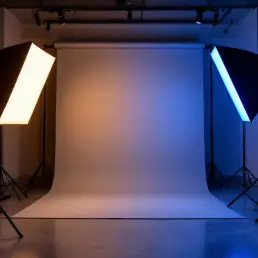 Portrait subject in professional photography studio with dramatic bi-color LED lighting, warm amber and cool blue panels
