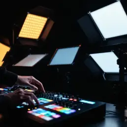 Professional lighting technician adjusts bi-color LED panels on stands with control console in modern studio setup