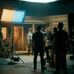 Bi-colour LED film light on a stand splitting a cinematic set between warm amber and cool daylight-blue tones with shallow depth of field.
