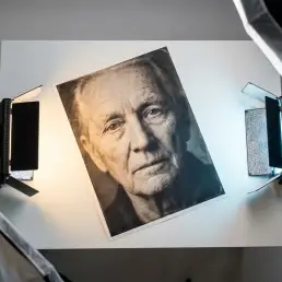 Fine-art portrait print on white surface lit by split bi-colour LED panel showing warm amber and cool daylight colour rendering across skin tones.